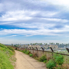 Fototapeta na wymiar Square Narrow trail pathway under cloudy blue sky in Huntington Beach California