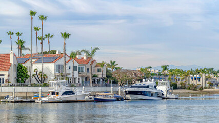 Fototapeta premium Pano Sea and houses with boats and docks against clouds and blue sky background
