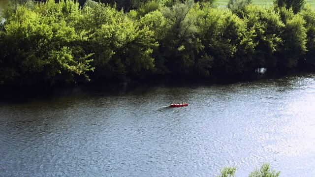 Red kayak with two people rowing through river on sunny day