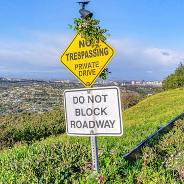 Square No Trespassing and Do Not Block Driveway sign at a private road in San Diego CA