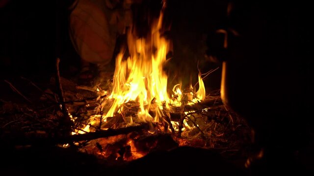 Night bonfire. People sit in the dark by the fire and warm themselves. Camping by the fire 4k