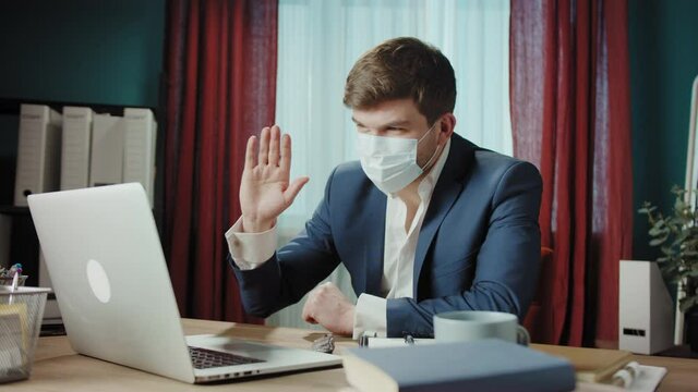 Executive senior CEO businessman in medical mask using online meeting virtual conference with laptop, remote office, man talking. Financial director saying goodbye and closing computer, home office. 