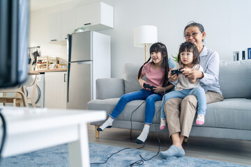 Asian happy family stay home, grandmother play game with little girl. 