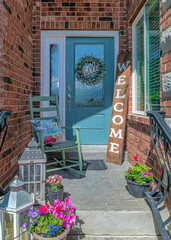 Vertical Cozy home entrance with flowers blue door sidelight and wreath at the portico