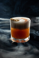 Whiskey stout sour in smoke on black background