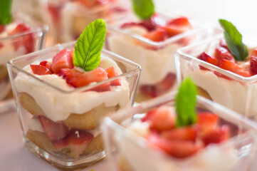 Postre coctelero de fresa con crema y galleta con menta en mini vaso postrero 