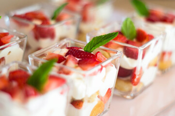 Postre coctelero de fresa con crema y galleta con menta en mini vaso postrero 