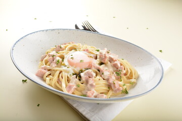 carbonara pasta with chicken ham and half boiled egg in creamy cheese white sauce in white background western halal menu