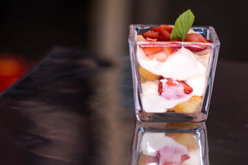 Postre coctelero de fresa con crema y galleta con menta en mini vaso postrero 