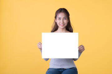 Fototapeta na wymiar Asian woman in casual clothes holding empty blank board isolated on yellow background
