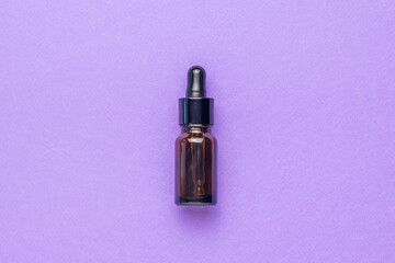 A bottle of medicine made of dark glass on a purple background. Flat lay.