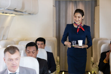 flight attendant serving water and cup of tea or coffee to passenger in airplane