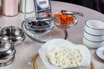 In a plate of cottage cheese, dried fruits and jam in bowls.