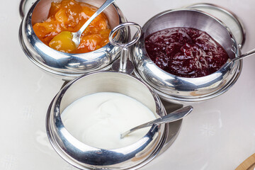 Sour cream and jam in bowls.