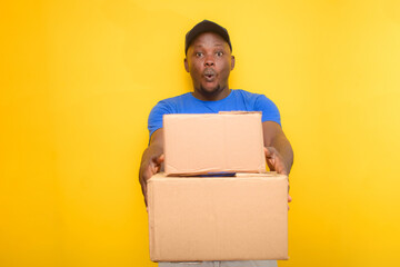 An African delivery or dispatch man with blue shirt carrying boxes and wearing a face cap