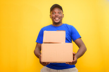 An African delivery or dispatch man with blue shirt carrying boxes and wearing a face cap