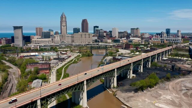 Aerial drone forward dolly shot of Cleveland Ohio skyline with cars driving on Hope Memorial bridge which passes over Cuyahoga river in foreground on a sunny afternoon