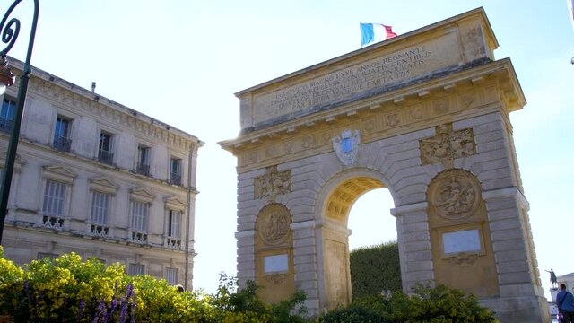 the triumphal arch of montpellier with the rays of the sun and the French flag which flies at its top