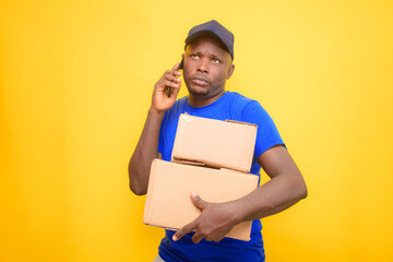 An African dispatch man with back pack, making a call, carrying boxes and wearing a face cap