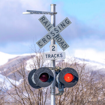 Square Grade crossing signal with red light gate and crossbuck at railroad crossing