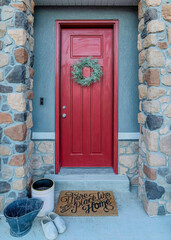 Vertical Red front door with wreath and portico with stone columns at the home entrance