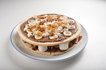 baked chocolate banana pizza with marshmallow and dry grape fruit dessert for kids in white background western halal menu