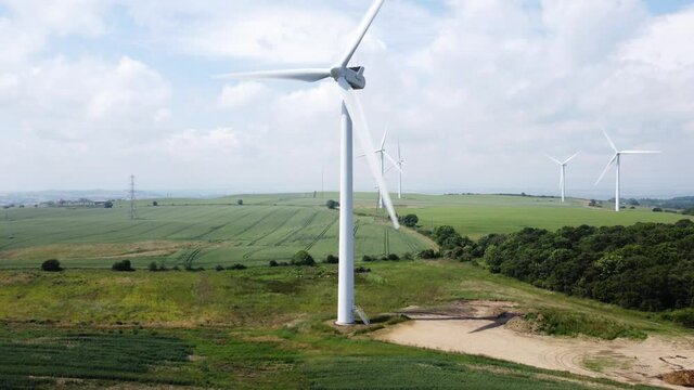 Wind Turbine rotating in field on cloudy hot summer day.
