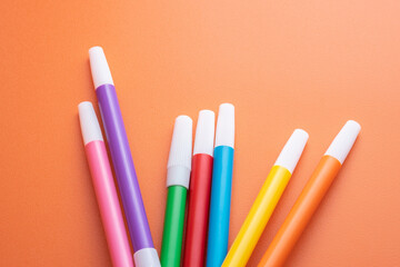 Colorful markers on orange background