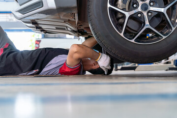 car mechanic adjusting tension in vehicle suspension Element at auto repair service center, car...