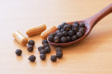 Black pepper and turmeric powder capsule isolated on wood table background.  