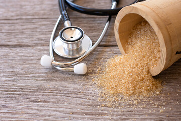 Brown sugar and medical stethoscope isolated on wood table background . Copy space.