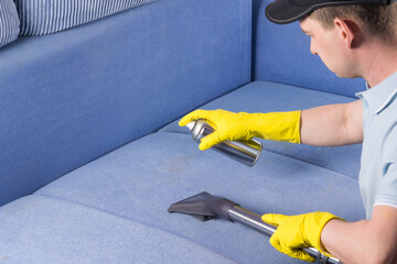 a man from the cleaning service cleans the upholstery of the sofa