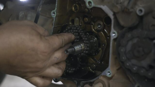 Mechanic put on a chain magnetic wheels on motorcycle engine mechanic, the motorbike in the shop, automatic motorbike repair