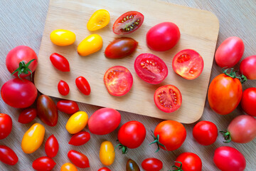 Fresh tomatoes of various colors, sizes, varieties on a wooden floor.