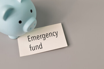 Piggy bank and white note written with EMERGENCY FUND.