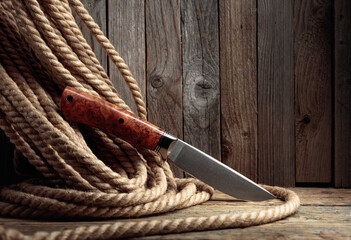Hunter combat hand made knife and hemp rope on wooden background.