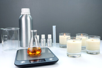 chemical beaker is on the digital scales, on white table with fragrance,  essential oil bottles and...