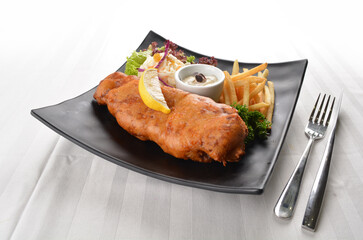 chef deep fried golden fish and chips with tartar sauce, lemon , French fries and salad dressing in plate on white table restaurant luxury hotel western cafe halal menu