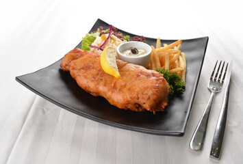 deep fried golden fish and chips with tartar sauce, lemon , French fries and salad dressing in white background western halal menu