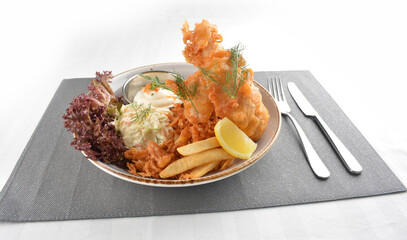 deep fried golden fish and chips with tartar sauce, lemon , French fries and salad dressing in white background western halal menu