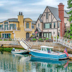 Fototapeta na wymiar Square Boats on canal and elegant houses in Long Beach with picture perfect scenery