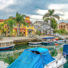 Square Small boats docked on canal in front of elegant houses in Long Beach California