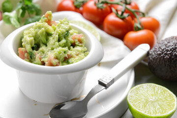 Bowl with tasty guacamole and lime on table, closeup