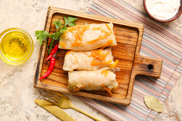 Board with tasty stuffed cabbage rolls on grunge background