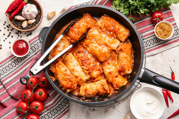 Frying pan with tasty stuffed cabbage rolls on light background
