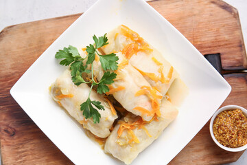 Plate with tasty stuffed cabbage rolls on wooden background