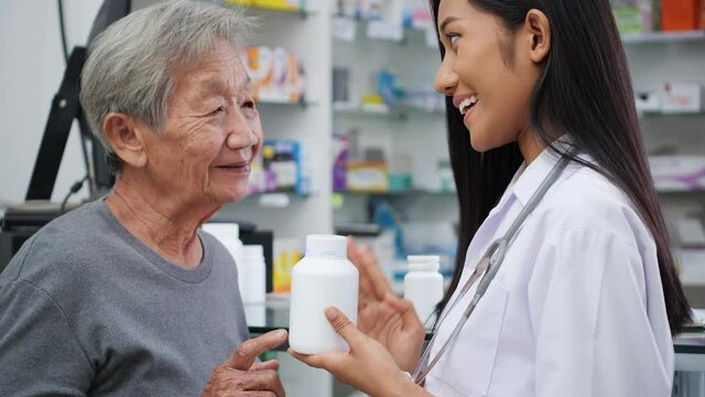 Pharmacist woman advice elderly female about treatment with medicine in pharmacy store at hospital. Asian senior women discuss medication with young doctor.