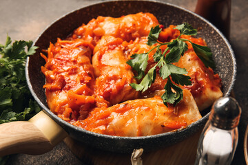 Frying pan with tasty stuffed cabbage rolls on dark background