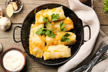 Frying pan with tasty stuffed cabbage rolls on wooden background