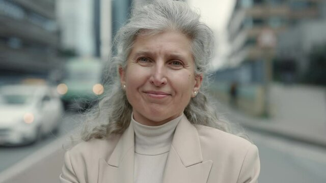 Woman with grey hair standing on street of big city